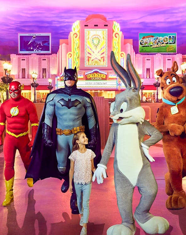 Child walking with Warner Bros characters at Abu Dhabi theme park.