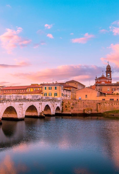Tiberius Bridge over the Marecchia River at sunset in Rimini, Italy.