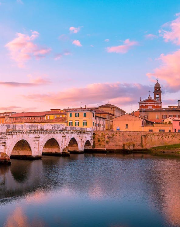 Tiberius Bridge over the Marecchia River at sunset in Rimini, Italy.