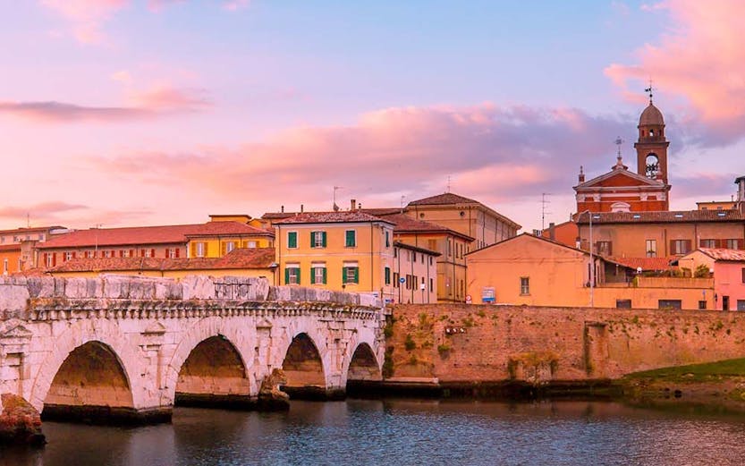 Tiberius Bridge over the Marecchia River at sunset in Rimini, Italy.