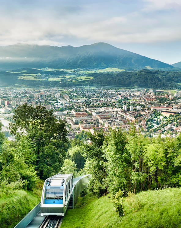 Funicular ascending Nordkette mountain with Innsbruck cityscape in the background.