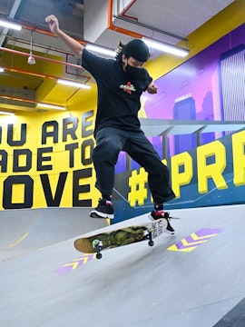 Skateboarder performing trick at SuperPark Singapore indoor skate area.