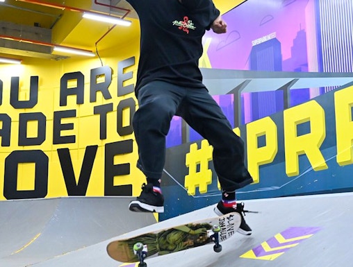 Skateboarder performing trick at SuperPark Singapore indoor skate area.
