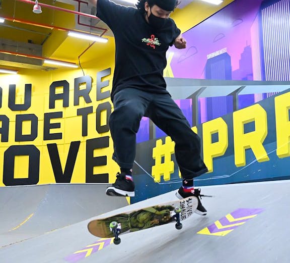 Skateboarder performing trick at SuperPark Singapore indoor skate area.