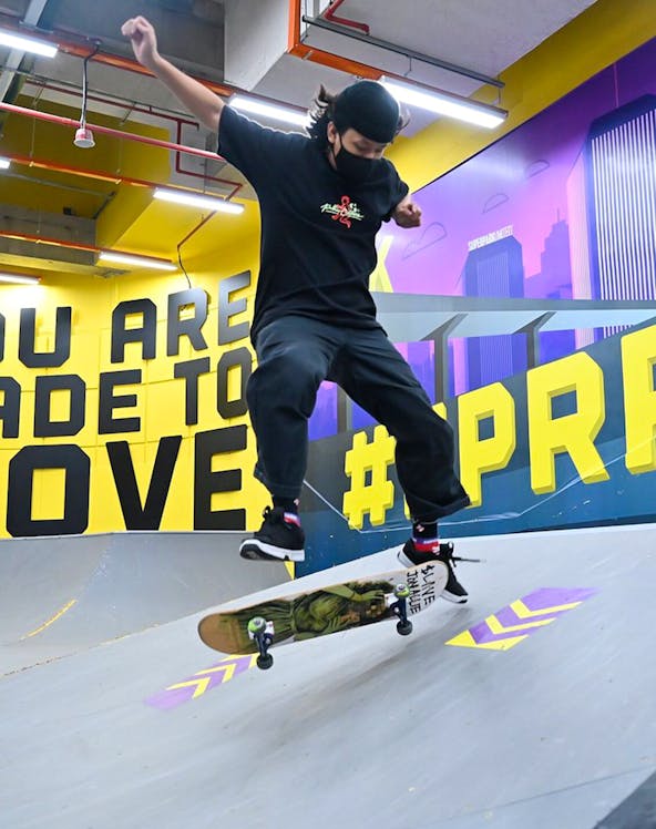 Skateboarder performing trick at SuperPark Singapore indoor skate area.