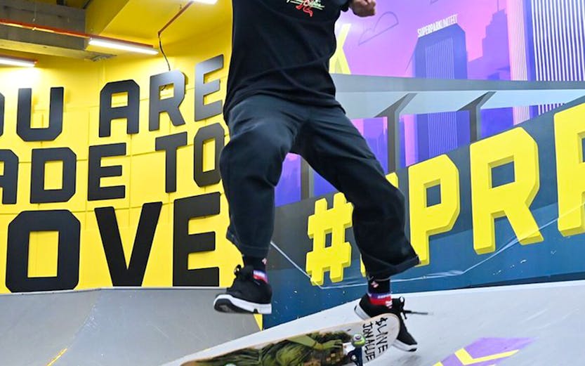 Skateboarder performing trick at SuperPark Singapore indoor skate area.
