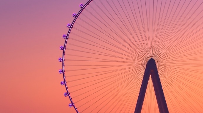 Ferris wheel at sunset in Dubai with city lights in the background.