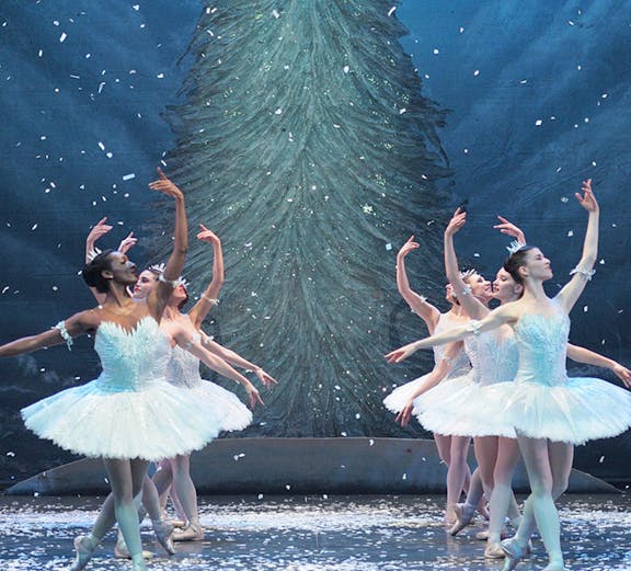 Ballet dancers performing in front of a Christmas tree during a London show.