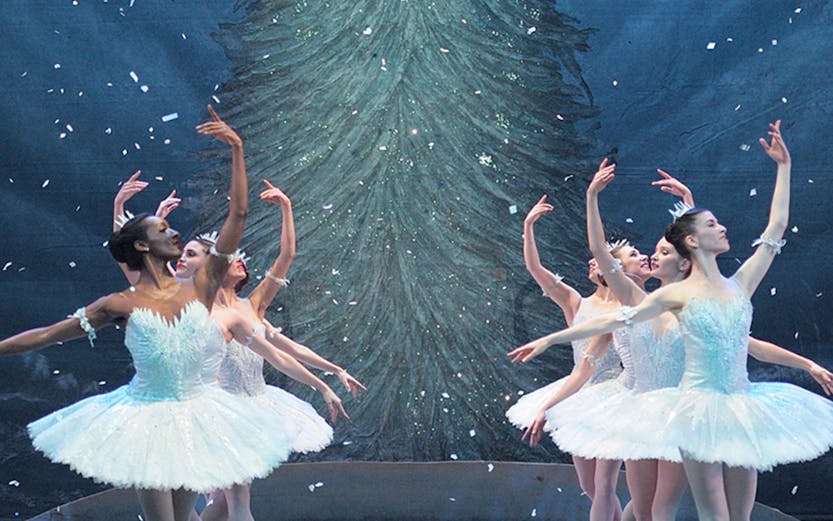 Ballet dancers performing in front of a Christmas tree during a London show.
