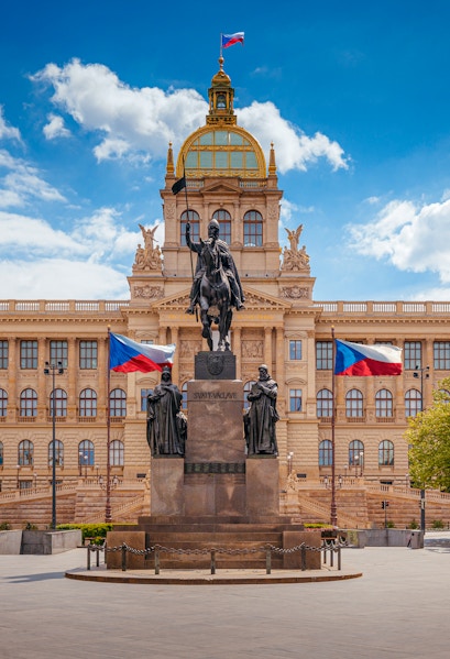 Equestrian statue in front of Prague National Museum with Czech flags.