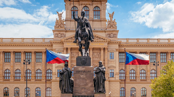 Equestrian statue in front of Prague National Museum with Czech flags.