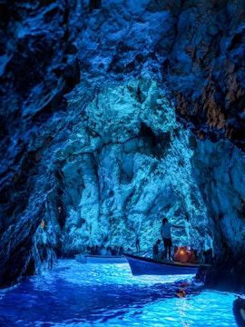 Boats with tourists exploring the illuminated Blue Cave in Croatia.