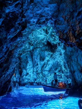 Boats with tourists exploring the illuminated Blue Cave in Croatia.