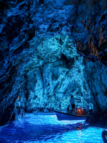 Boats with tourists exploring the illuminated Blue Cave in Croatia.