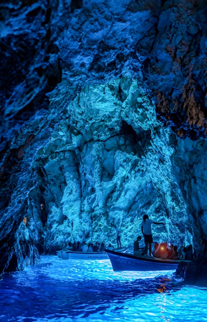 Boats with tourists exploring the illuminated Blue Cave in Croatia.