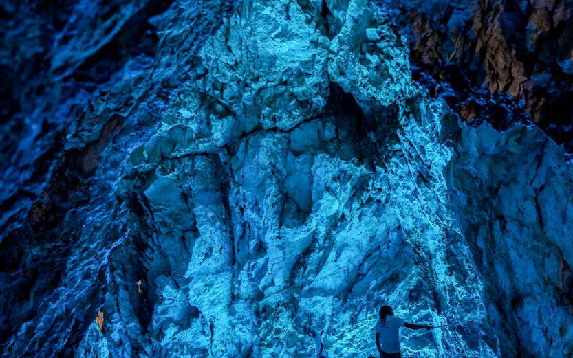 Boats with tourists exploring the illuminated Blue Cave in Croatia.