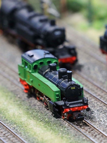 Miniature green train on tracks at Hzero Railway exhibit.