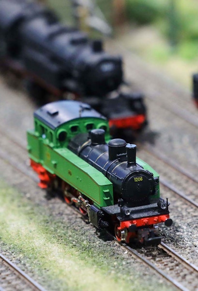 Miniature green train on tracks at Hzero Railway exhibit.