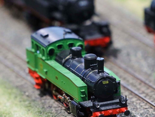 Miniature green train on tracks at Hzero Railway exhibit.