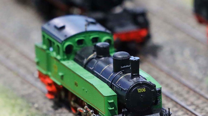 Miniature green train on tracks at Hzero Railway exhibit.