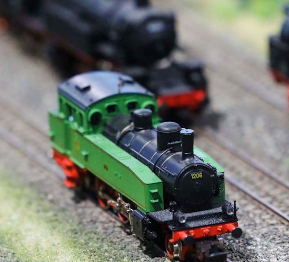 Miniature green train on tracks at Hzero Railway exhibit.