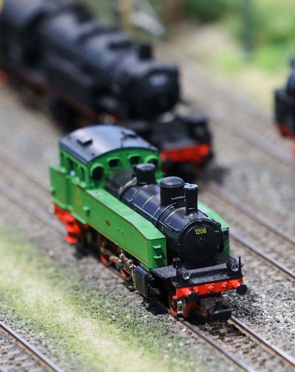 Miniature green train on tracks at Hzero Railway exhibit.