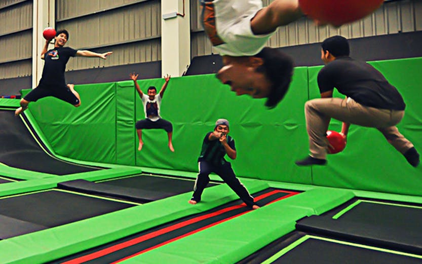People playing dodgeball on trampolines at Jump Street Asia indoor park.