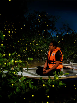 Person in a boat surrounded by fireflies on Kuala Selangor Fireflies Tour.