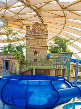 Aquaworld Budapest indoor water slide with temple-themed decor and lush greenery.
