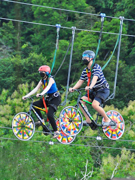 Two people riding bicycles on a high wire at Xtreme Park Langkawi.