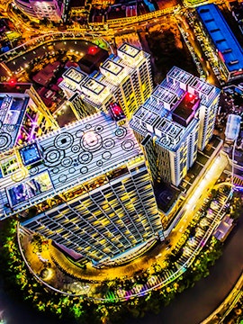 Aerial view of The Shore Sky Tower in Melaka, illuminated at night with surrounding cityscape.