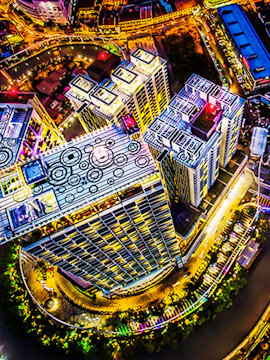 Aerial view of The Shore Sky Tower in Melaka, illuminated at night with surrounding cityscape.