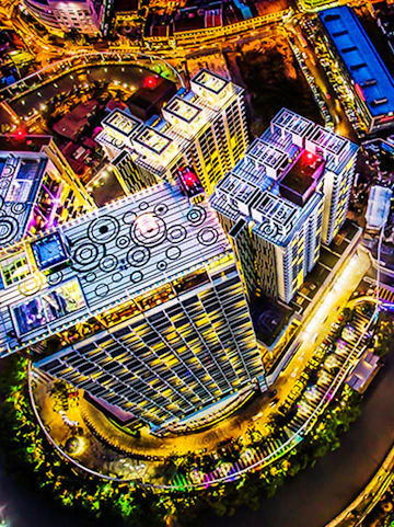 Aerial view of The Shore Sky Tower in Melaka, illuminated at night with surrounding cityscape.