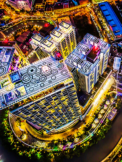 Aerial view of The Shore Sky Tower in Melaka, illuminated at night with surrounding cityscape.