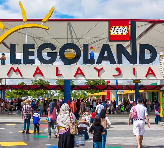 Visitors entering Legoland Malaysia theme park under the main entrance sign.