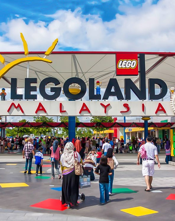 Visitors entering Legoland Malaysia theme park under the main entrance sign.