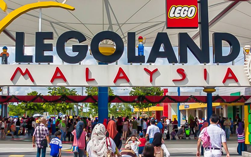 Visitors entering Legoland Malaysia theme park under the main entrance sign.
