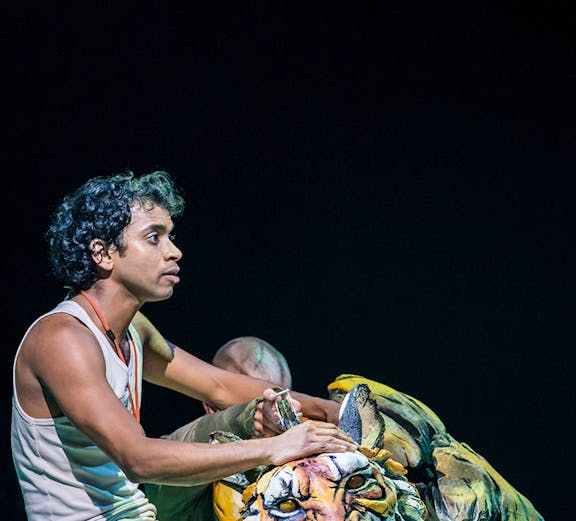 Performer with tiger puppet in a theatrical show.