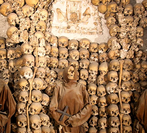 Capuchin Crypt in Rome with monk statue and skulls on display.