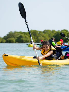 Kayaking on calm waters in Doha with lush greenery in the background.