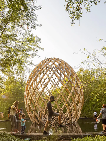 Geometric wooden structure on Al Noor Island, Sharjah, surrounded by lush greenery and visitors.