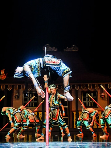 Performers in traditional costumes during Devdan Show, Bali, executing a dramatic acrobatic act.