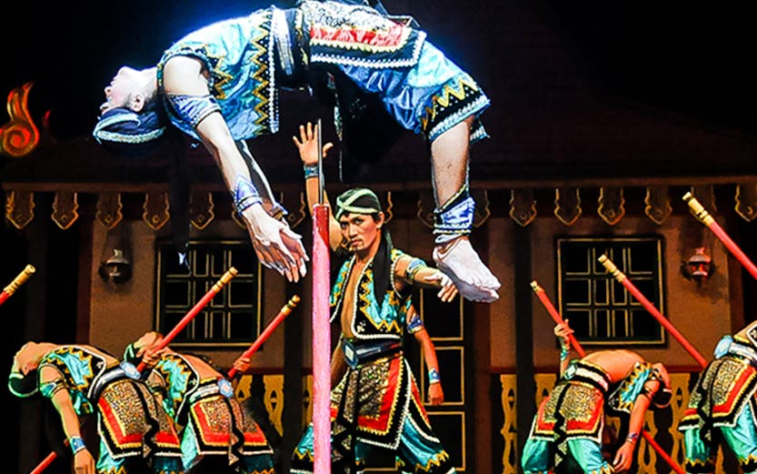 Performers in traditional costumes during Devdan Show, Bali, executing a dramatic acrobatic act.