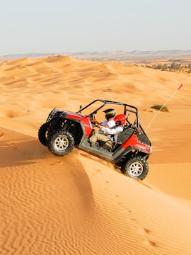 Dune buggy driving over sand dunes in Dubai desert safari.