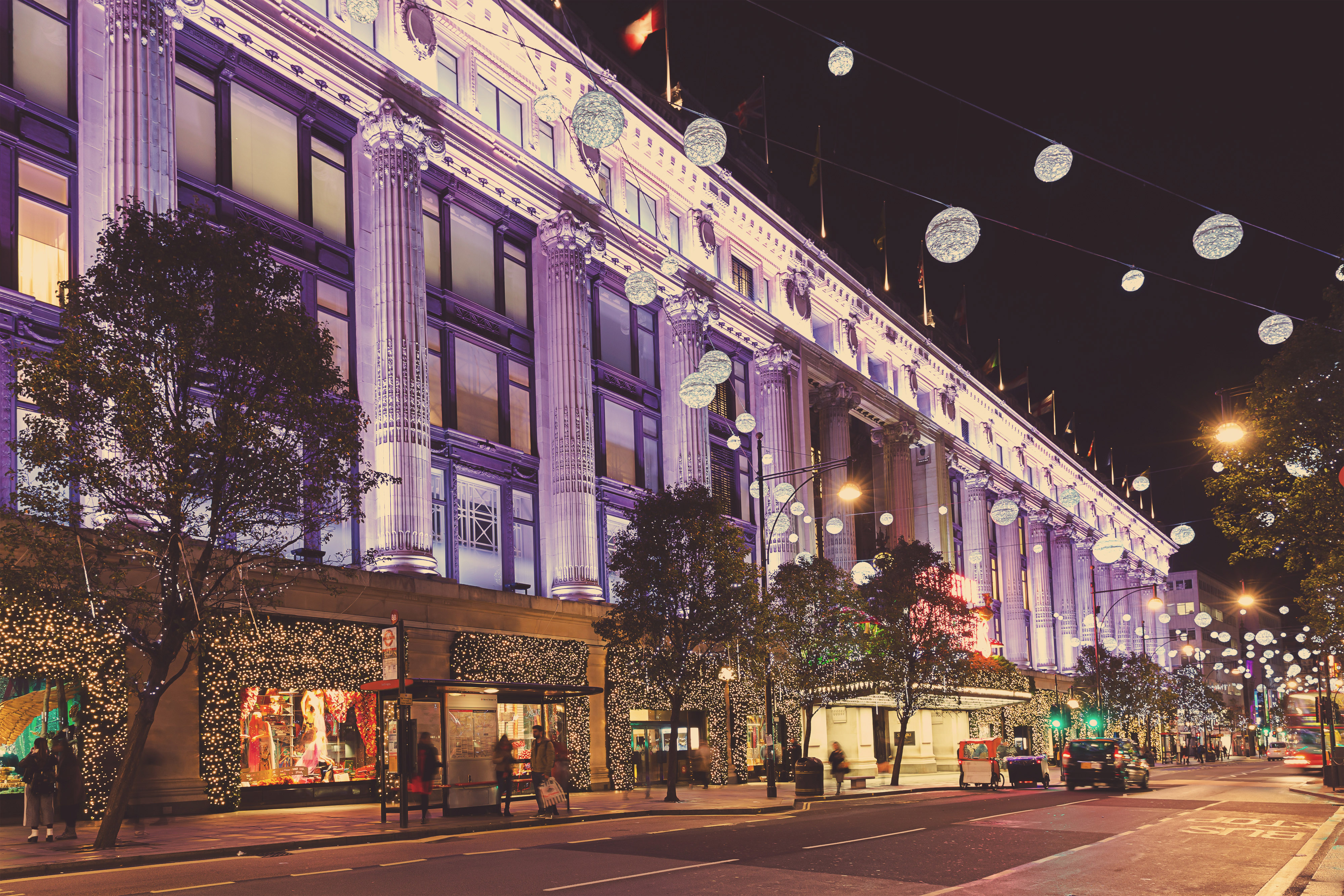 Selfridges department store in London illuminated at night with festive lights.