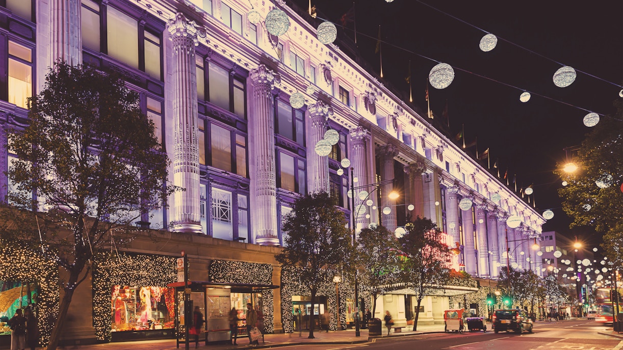 Selfridges department store in London illuminated at night with festive lights.