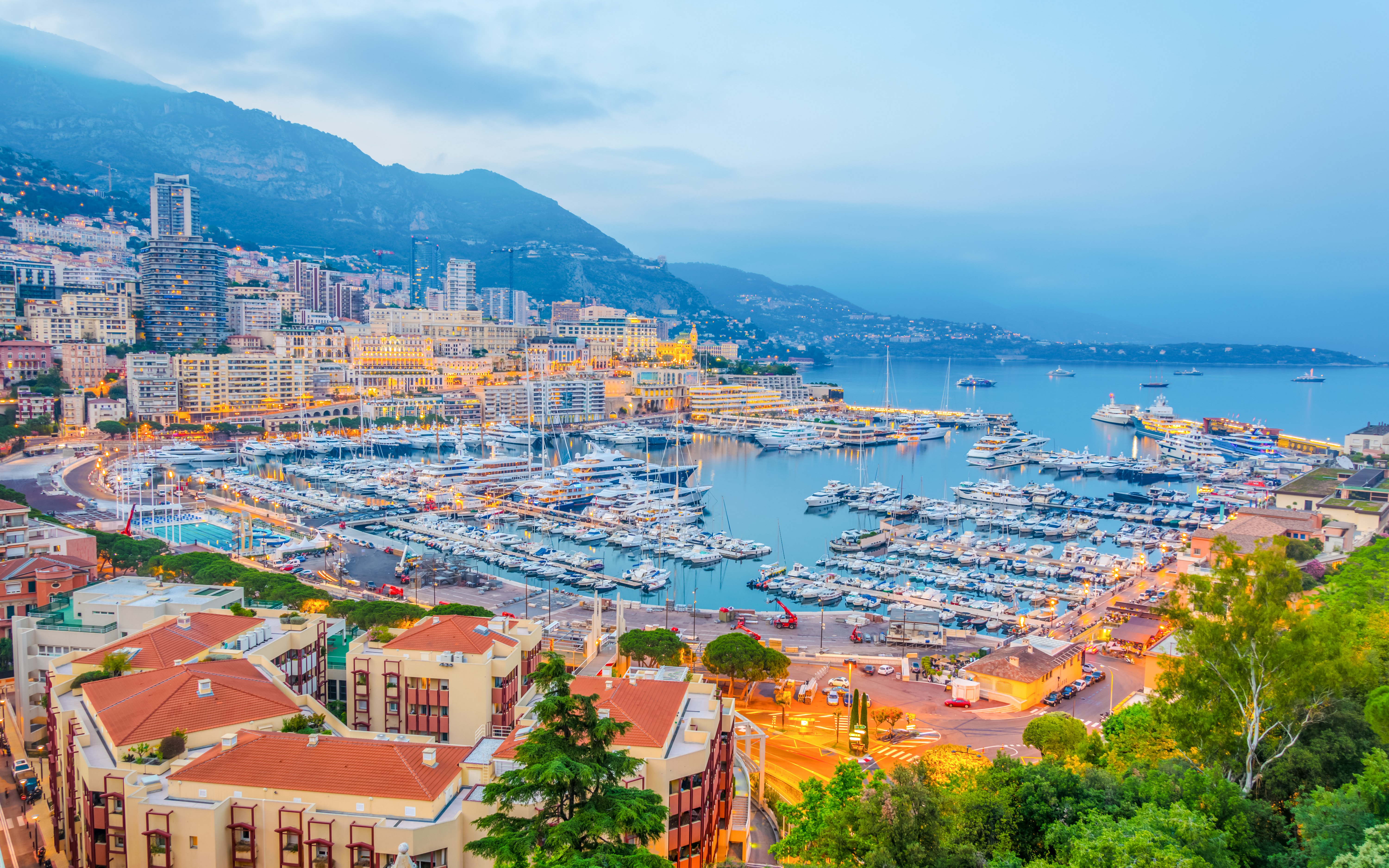 Port Hercules in Monaco with yachts and cityscape at dusk.