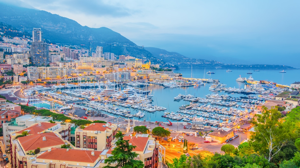 Port Hercules in Monaco with yachts and cityscape at dusk.