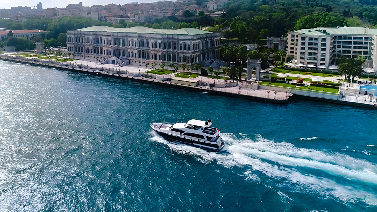 Bosphorus yacht cruising past Dolmabahçe Palace, Istanbul, aerial view.