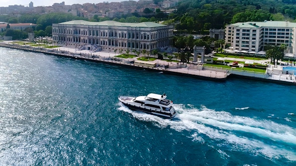 Bosphorus yacht cruising past Dolmabahçe Palace, Istanbul, aerial view.